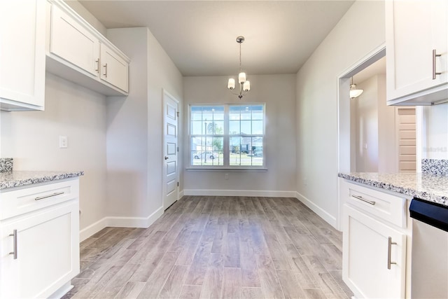 kitchen featuring light wood finished floors, stainless steel dishwasher, white cabinetry, light stone countertops, and pendant lighting