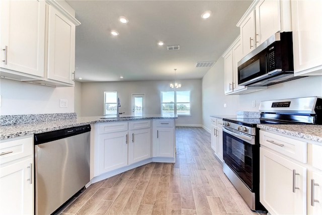 kitchen featuring stainless steel appliances, a sink, a chandelier, light wood finished floors, and white cabinets