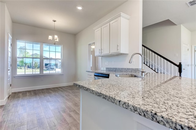 kitchen featuring a sink, light stone countertops, white cabinets, a chandelier, and light wood-style flooring