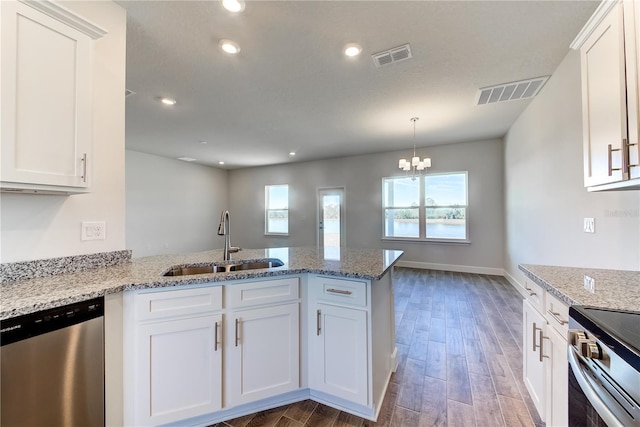 kitchen with stainless steel appliances, a sink, a peninsula, white cabinets, and recessed lighting