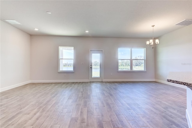 empty room featuring a chandelier, wood finished floors, baseboards, and recessed lighting
