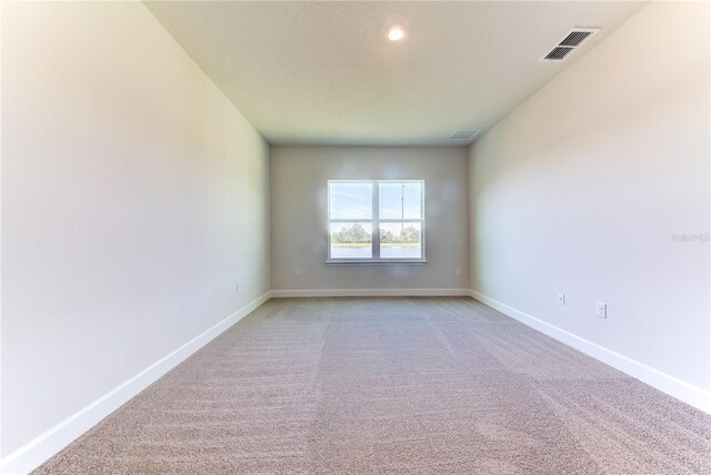 spare room featuring baseboards and light carpet