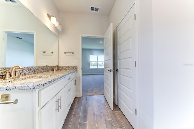 full bath with wood finished floors, double vanity, and baseboards