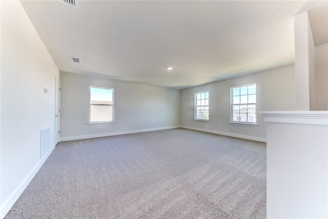 carpeted empty room featuring baseboards and plenty of natural light