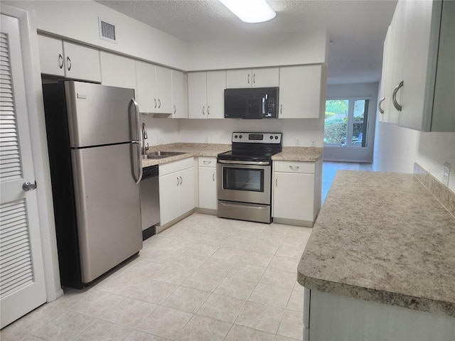 2293 Swedish Dr Unit 11, Clearwater, FL 33763 - kitchen with appliances with stainless steel finishes, a sink, light tile patterned floors, light countertops, and white cabinets