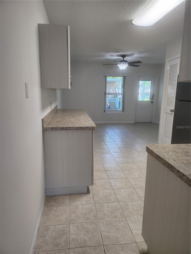 2293 Swedish Dr Unit 11, Clearwater, FL 33763 - kitchen with light tile patterned floors, baseboards, ceiling fan, freestanding refrigerator, and a textured ceiling