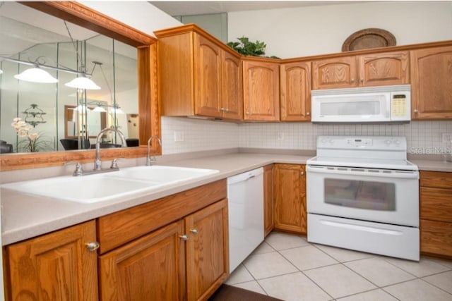 kitchen with white appliances, a sink, tasteful backsplash, light countertops, and brown cabinets
