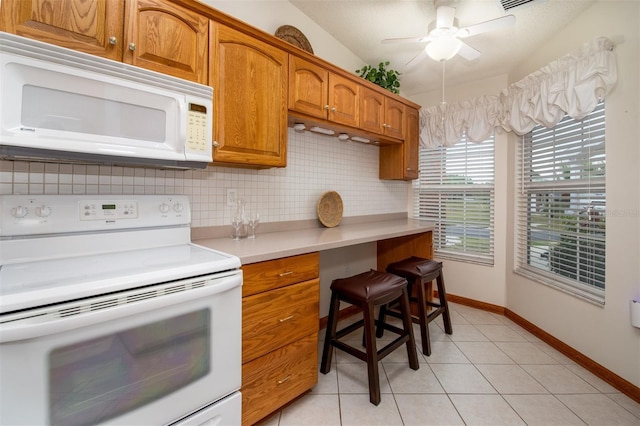 kitchen with white appliances, brown cabinets, backsplash, light countertops, and ceiling fan