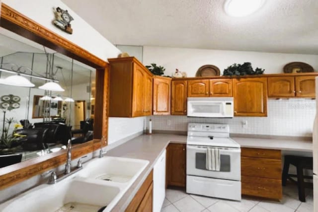 kitchen featuring white appliances, a sink, light tile patterned flooring, light countertops, and a textured ceiling