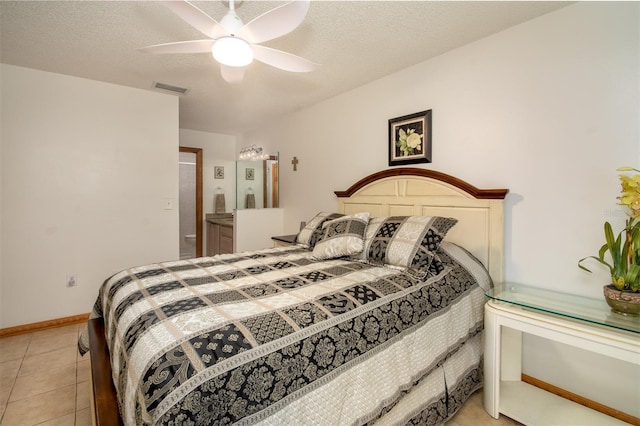 bedroom featuring light tile patterned floors, a textured ceiling, ceiling fan, ensuite bathroom, and baseboards