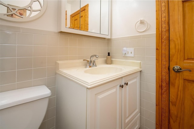 half bathroom featuring tile walls, vanity, and toilet