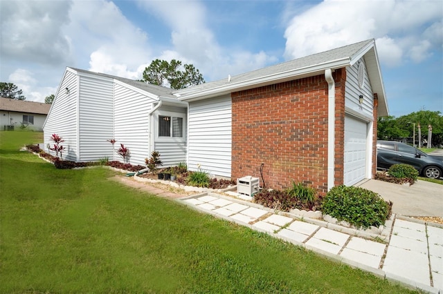 view of side of home with a lawn, brick siding, driveway, and an attached garage