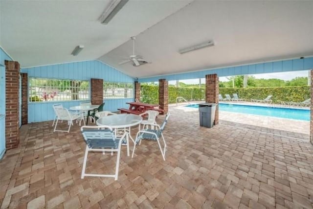 view of patio featuring a community pool, ceiling fan, and fence