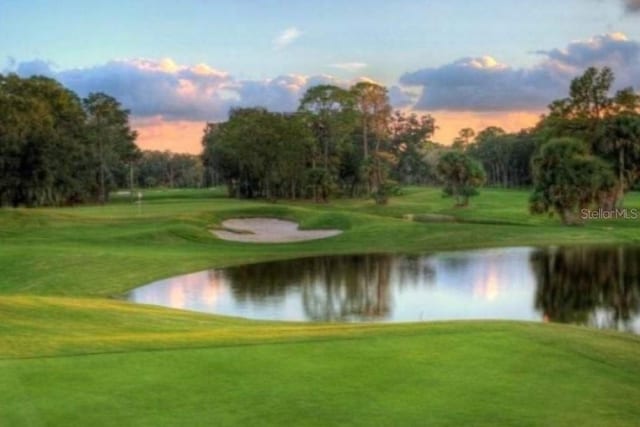view of property's community with a water view, golf course view, and a lawn