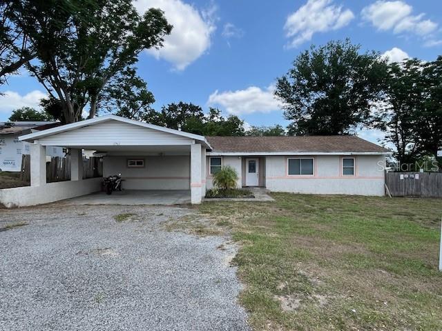 single story home with driveway, a carport, and stucco siding