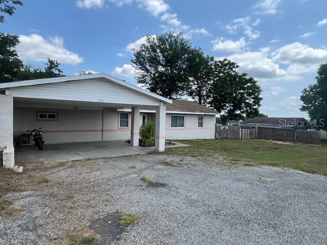 rear view of house featuring an attached carport and gravel driveway