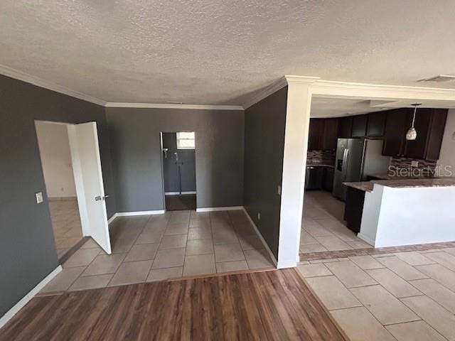 interior space featuring light tile patterned floors, ornamental molding, baseboards, and a textured ceiling
