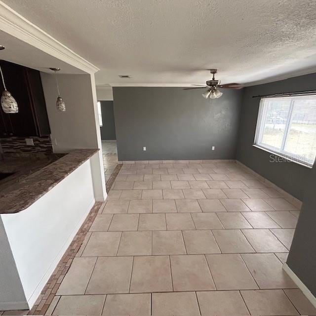 spare room with a textured ceiling, a ceiling fan, baseboards, and light tile patterned flooring