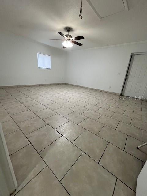 empty room featuring ceiling fan, light tile patterned floors, and ornamental molding