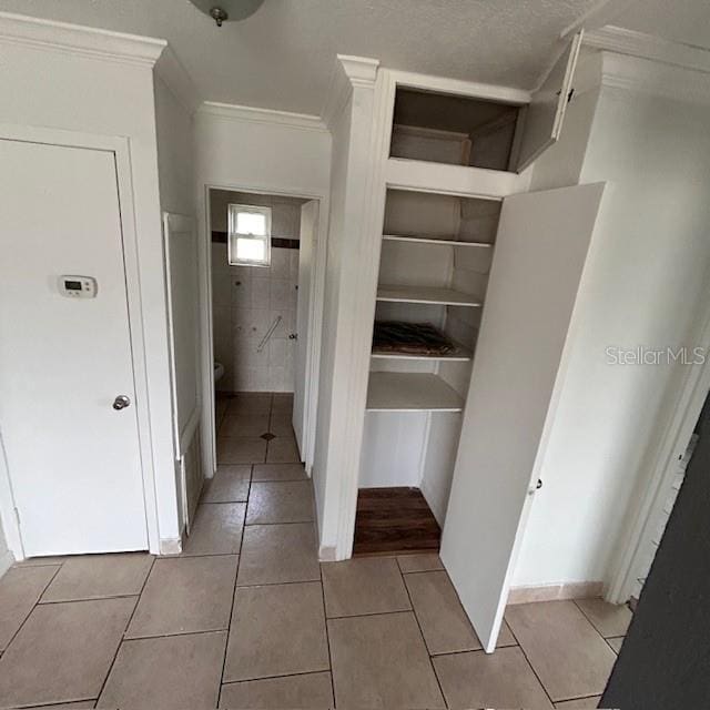bathroom with ornamental molding, tile patterned flooring, and toilet