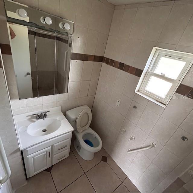 bathroom featuring tile walls, vanity, tile patterned floors, and toilet