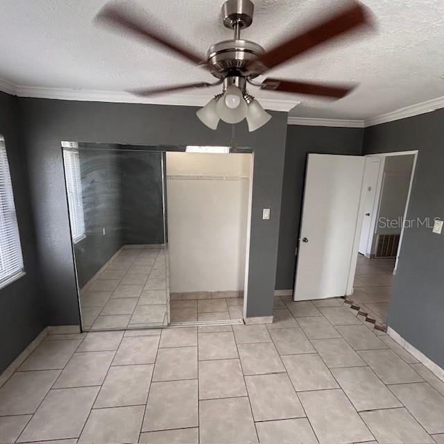 unfurnished dining area featuring a textured ceiling, ceiling fan, light tile patterned floors, ornamental molding, and baseboards