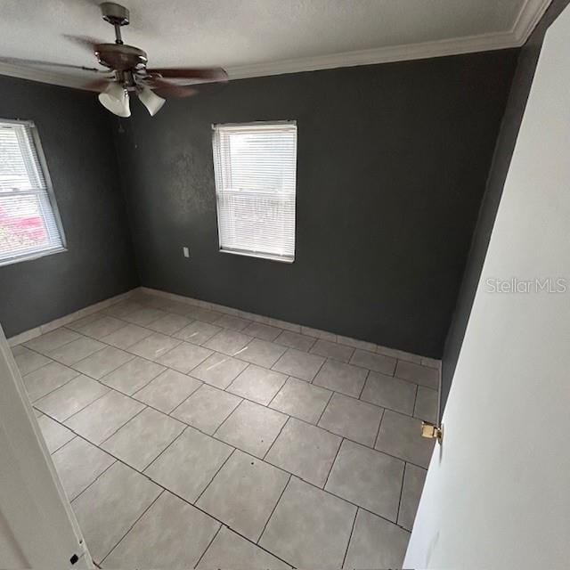 spare room with healthy amount of natural light, crown molding, ceiling fan, and light tile patterned flooring