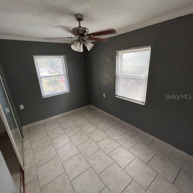 empty room featuring crown molding, ceiling fan, and light tile patterned floors
