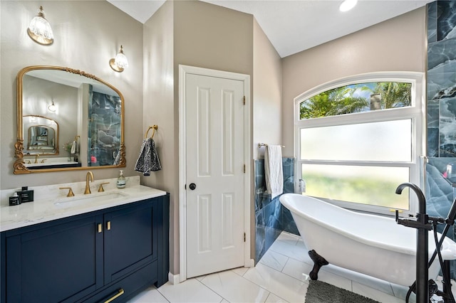 bathroom with a freestanding tub, vanity, and marble look tiles