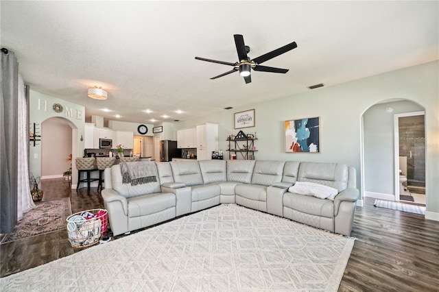 living area with arched walkways, ceiling fan, wood finished floors, and baseboards