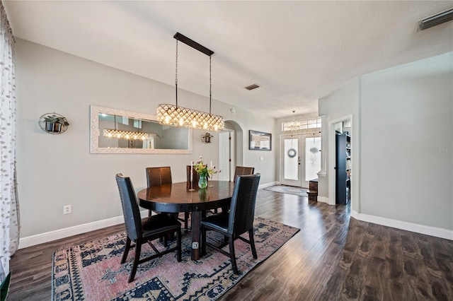 dining area with arched walkways, a chandelier, wood finished floors, and baseboards