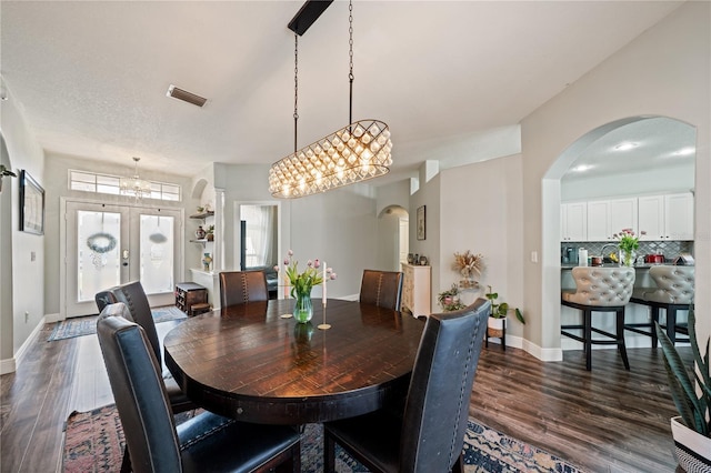 dining room with arched walkways, dark wood-style floors, baseboards, and a chandelier