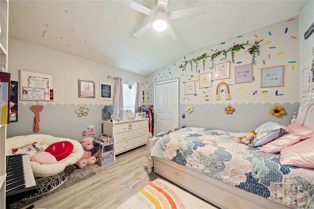 bedroom with light wood-type flooring, lofted ceiling, a closet, and a ceiling fan