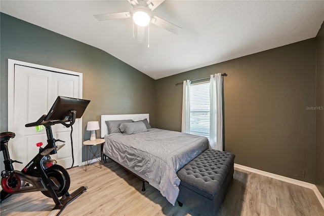 bedroom with lofted ceiling, light wood-type flooring, a ceiling fan, and baseboards