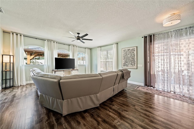 living area featuring ceiling fan, a textured ceiling, dark wood-style flooring, and baseboards