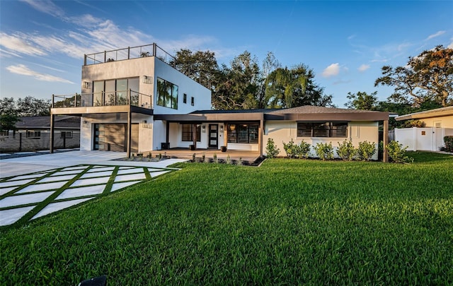rear view of house with a balcony, a garage, driveway, and stucco siding