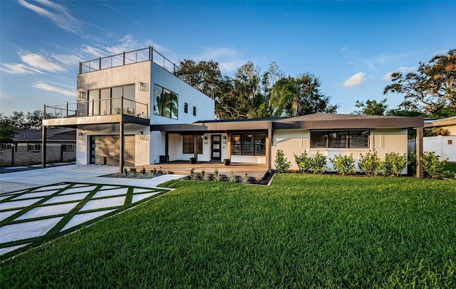 rear view of house featuring concrete driveway, a balcony, stucco siding, a porch, and an attached garage