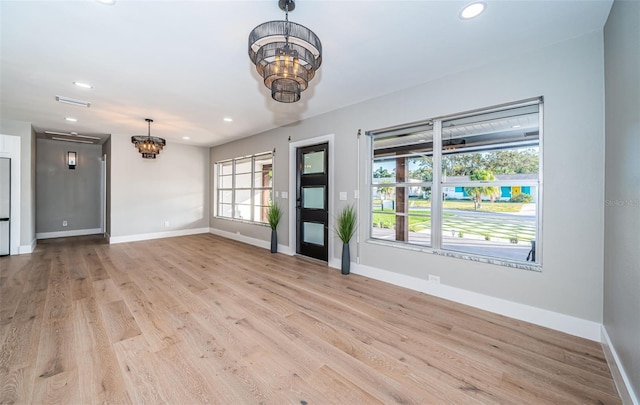 spare room with a chandelier, baseboards, recessed lighting, and light wood-style flooring