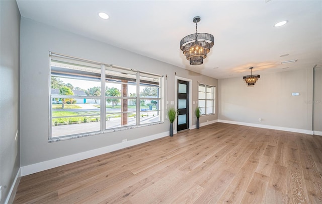 spare room with a chandelier, light wood-style floors, baseboards, and recessed lighting