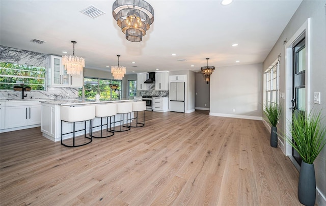 kitchen with a chandelier, wall chimney exhaust hood, white refrigerator, decorative backsplash, and stainless steel electric range oven