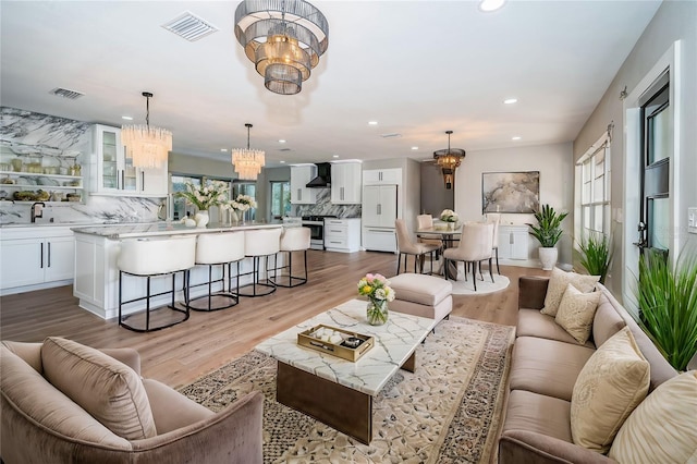 living area with a chandelier, recessed lighting, and light wood finished floors