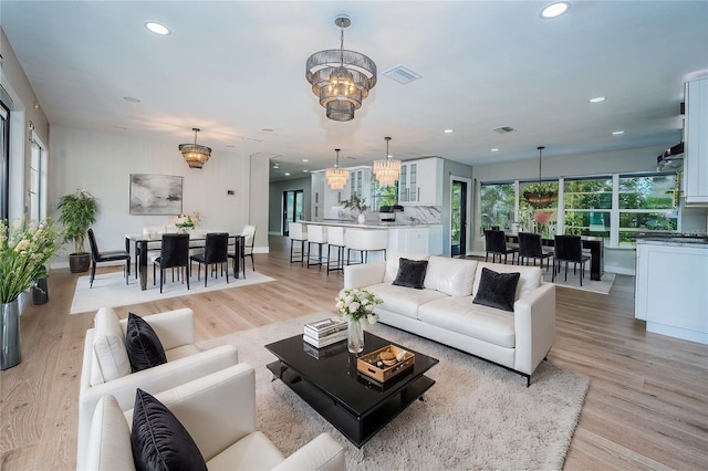 living room featuring recessed lighting, light wood-style flooring, and a chandelier