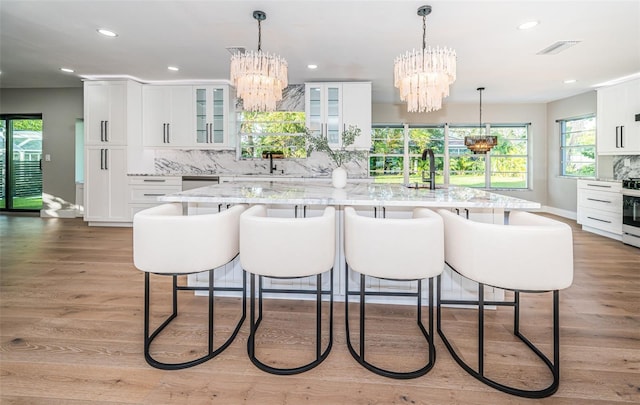 kitchen with a chandelier, a center island, white cabinets, baseboards, and recessed lighting