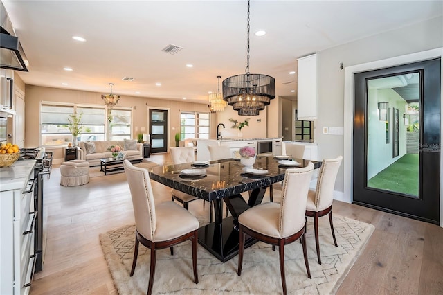 dining room with a chandelier, light wood finished floors, and recessed lighting