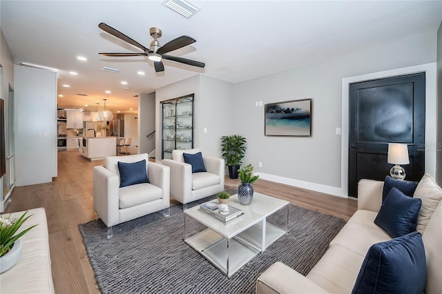 living area featuring a ceiling fan, light wood finished floors, recessed lighting, and baseboards
