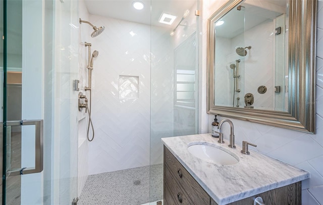 full bath featuring a shower stall, vanity, and tile walls