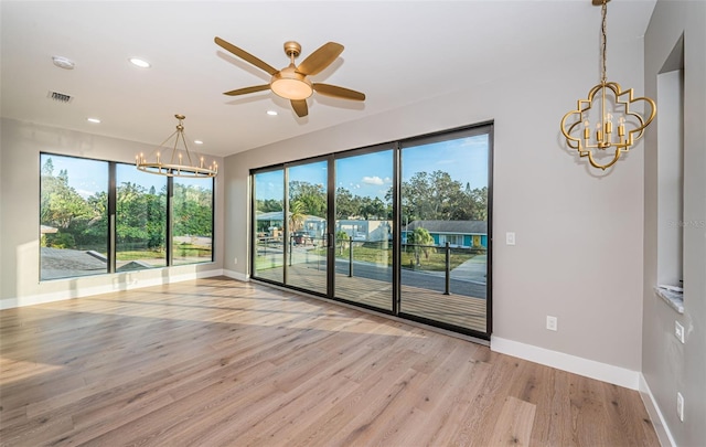 unfurnished room with a chandelier, baseboards, wood finished floors, ceiling fan, and recessed lighting