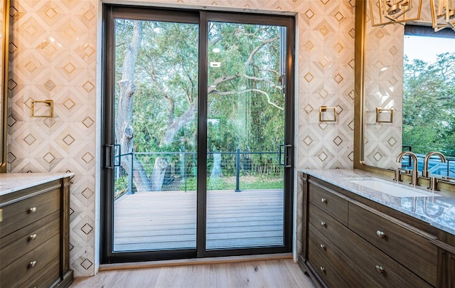 doorway to outside with a sink and light wood-style flooring