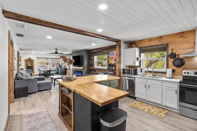 9821 113th St Unit 201, Seminole, FL 33772 - kitchen featuring butcher block countertops, appliances with stainless steel finishes, a sink, wood walls, and white cabinetry