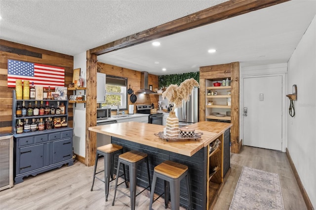 9821 113th St Unit 201, Seminole, FL 33772 - kitchen with wooden counters, stainless steel appliances, wall chimney range hood, light wood-style floors, and open shelves